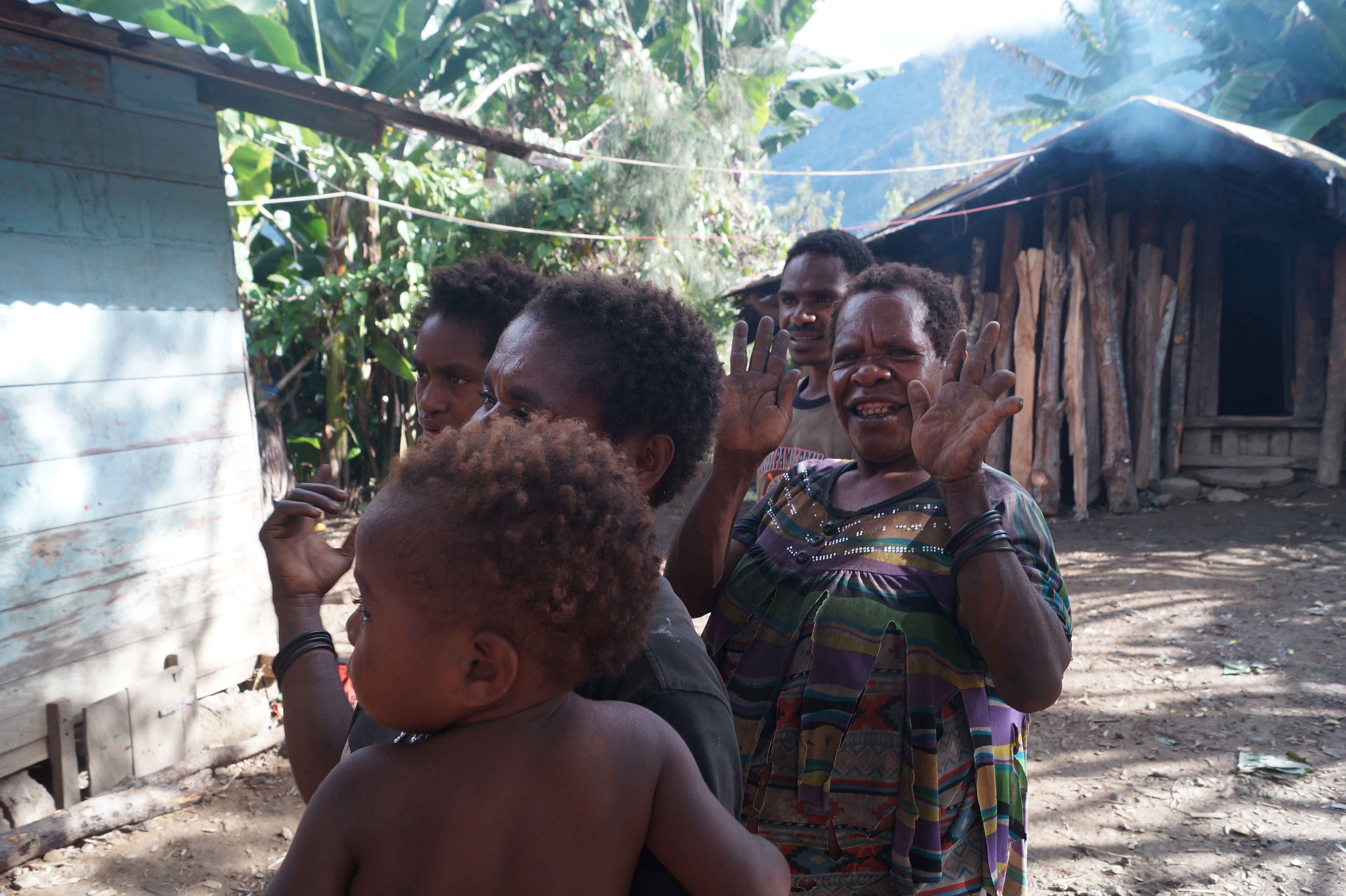 Satu Keluarga di Distrik Wandai, Papua sedang berkumpul di depan Honai. Satu orang mama menunjukan tangannya dan terlihat beberapa jarinya telah hilang, pertanda keluarga ini tidak benar-benar lengkap. 