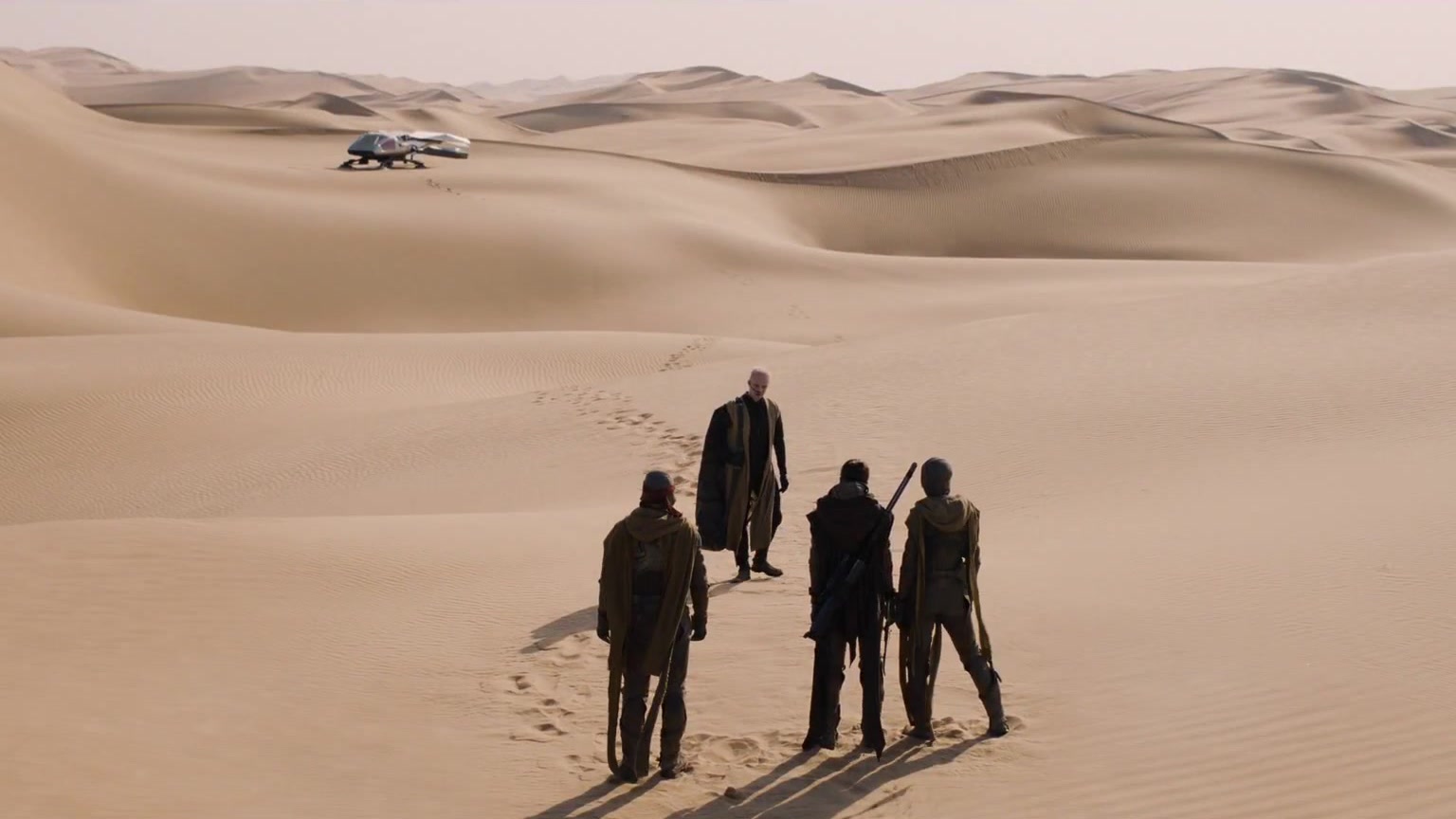 Empat sosok Fremen berjalan di bukit pasir Arrakis dengan ornithopter di kejauhan dalam trailer final Dune: Part Three