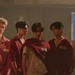 Member ENHYPEN berbaris dalam seragam merah di video musik Bloody Paradise