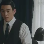 Park Jin-young sebagai Sato Hideo duduk di meja kerja dalam drama 100 Days of Deception