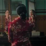 Perempuan berbaju merah bermotif bunga duduk di depan cermin dalam trailer film Pirunduk
