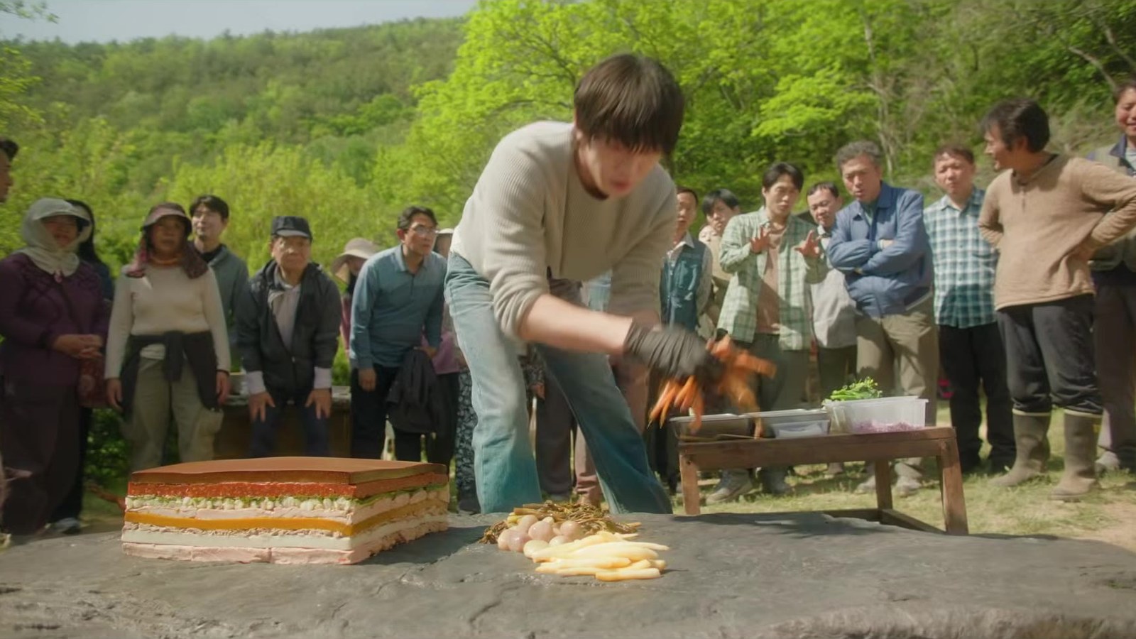Kang Han yang diperankan Ahn Hyo-seop memasak di atas batu di depan warga desa dalam Final Table