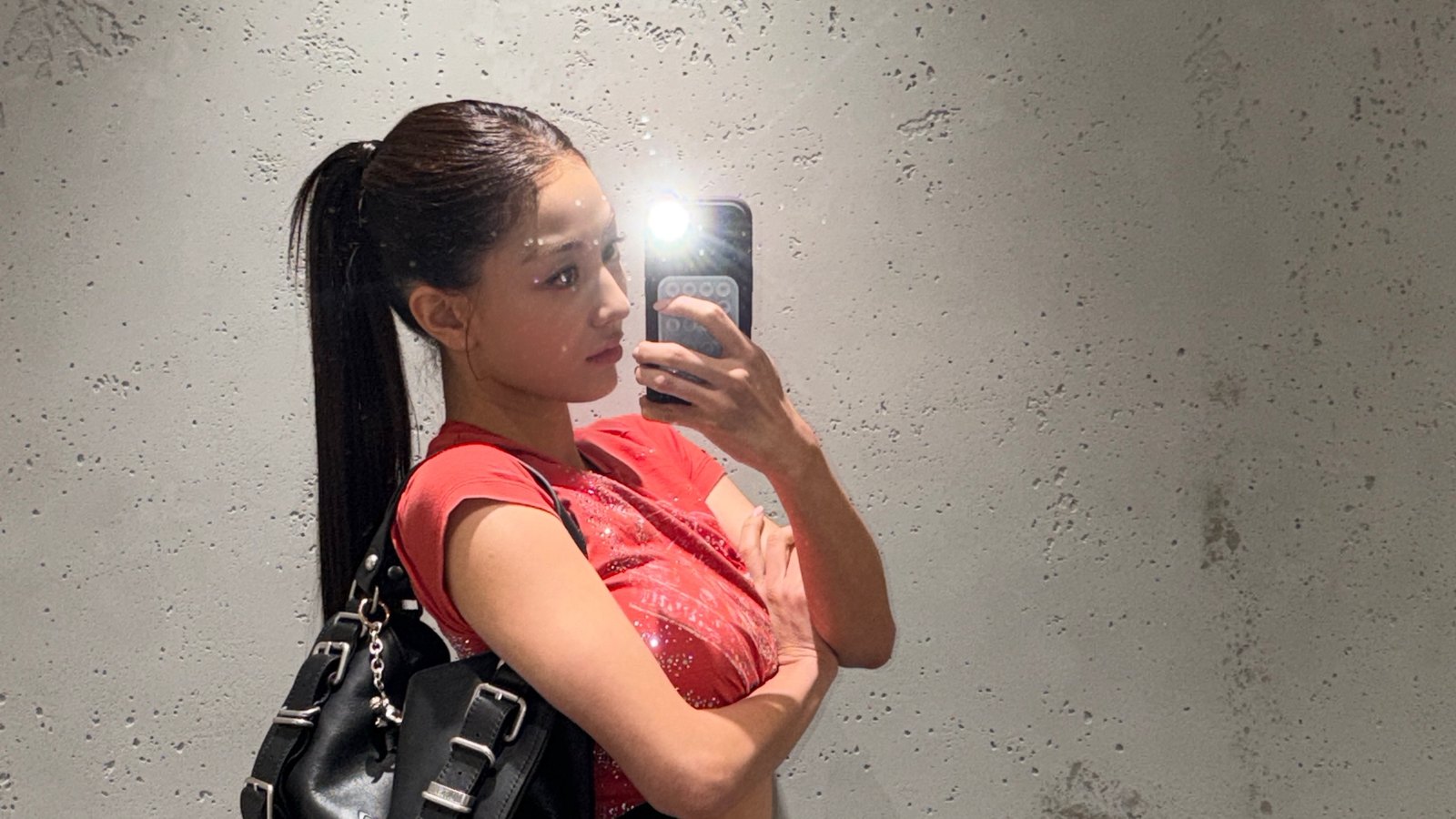 Jihyo berswafoto di depan cermin dengan kaus merah dan tas hitam