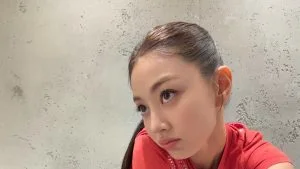 Jihyo TWICE dengan kaus merah berpose di depan dinding beton