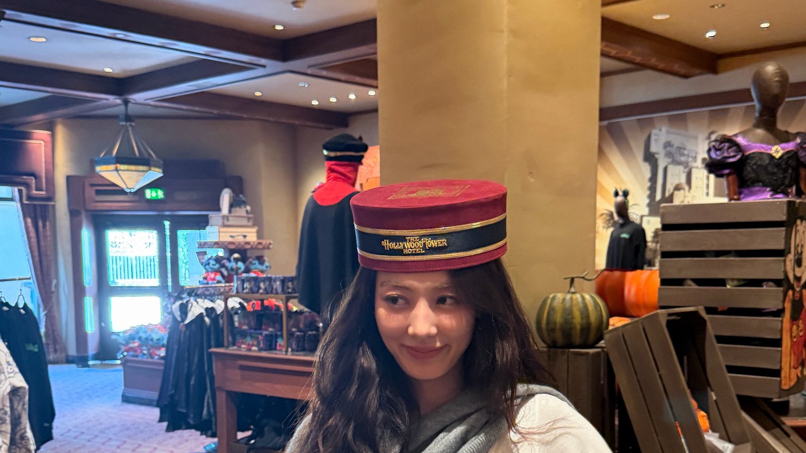 Jihyo TWICE tersenyum mengenakan topi merah di dalam sebuah toko