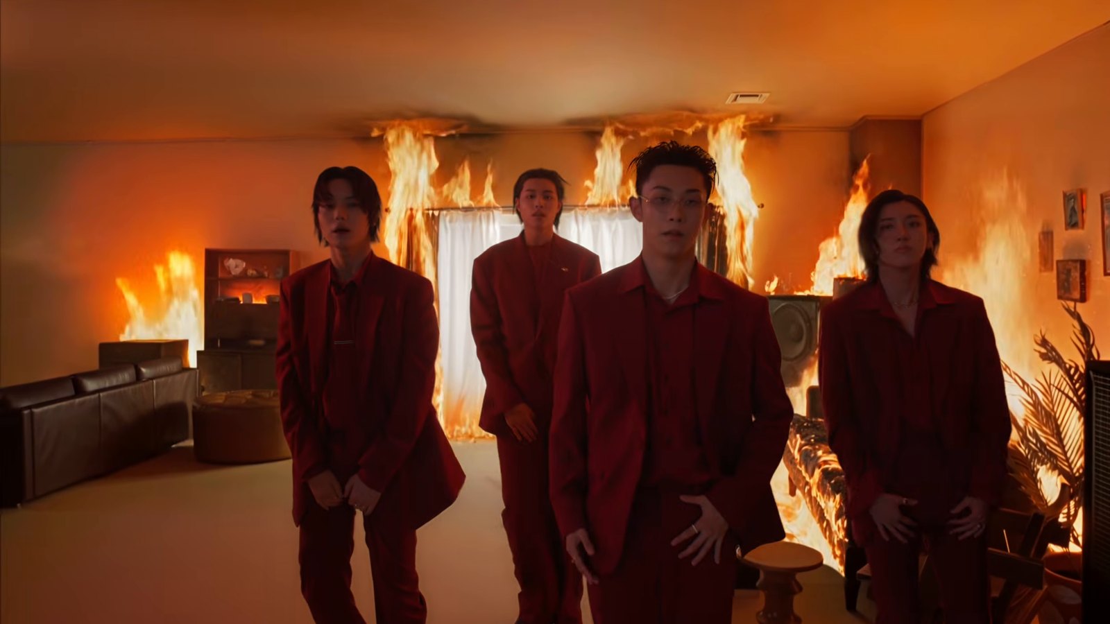 Keempat member LNGSHOT mengenakan setelan merah di ruangan yang terbakar dalam MV Masterpiece