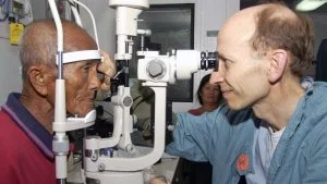 Dokter memeriksa mata pasien lanjut usia dengan slit lamp