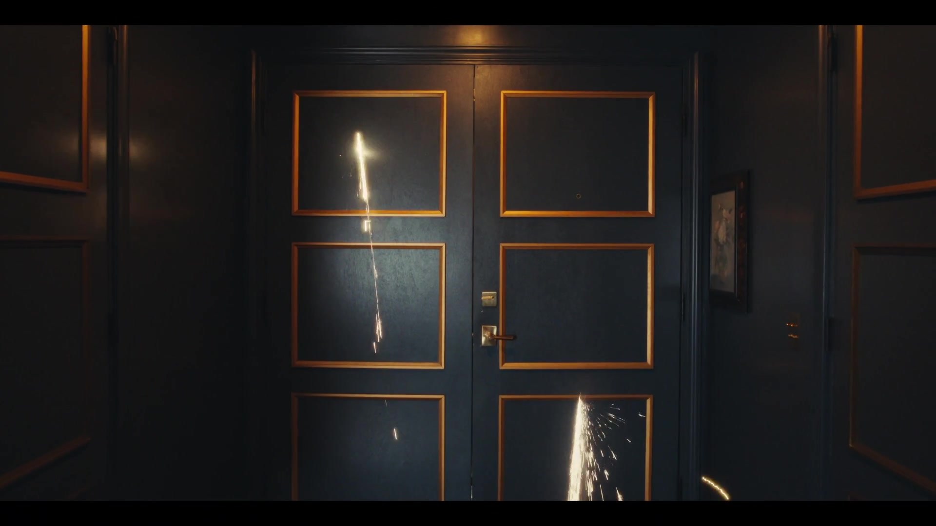 Percikan api menembus pintu kayu gelap di lorong dalam teaser MV Tarantino