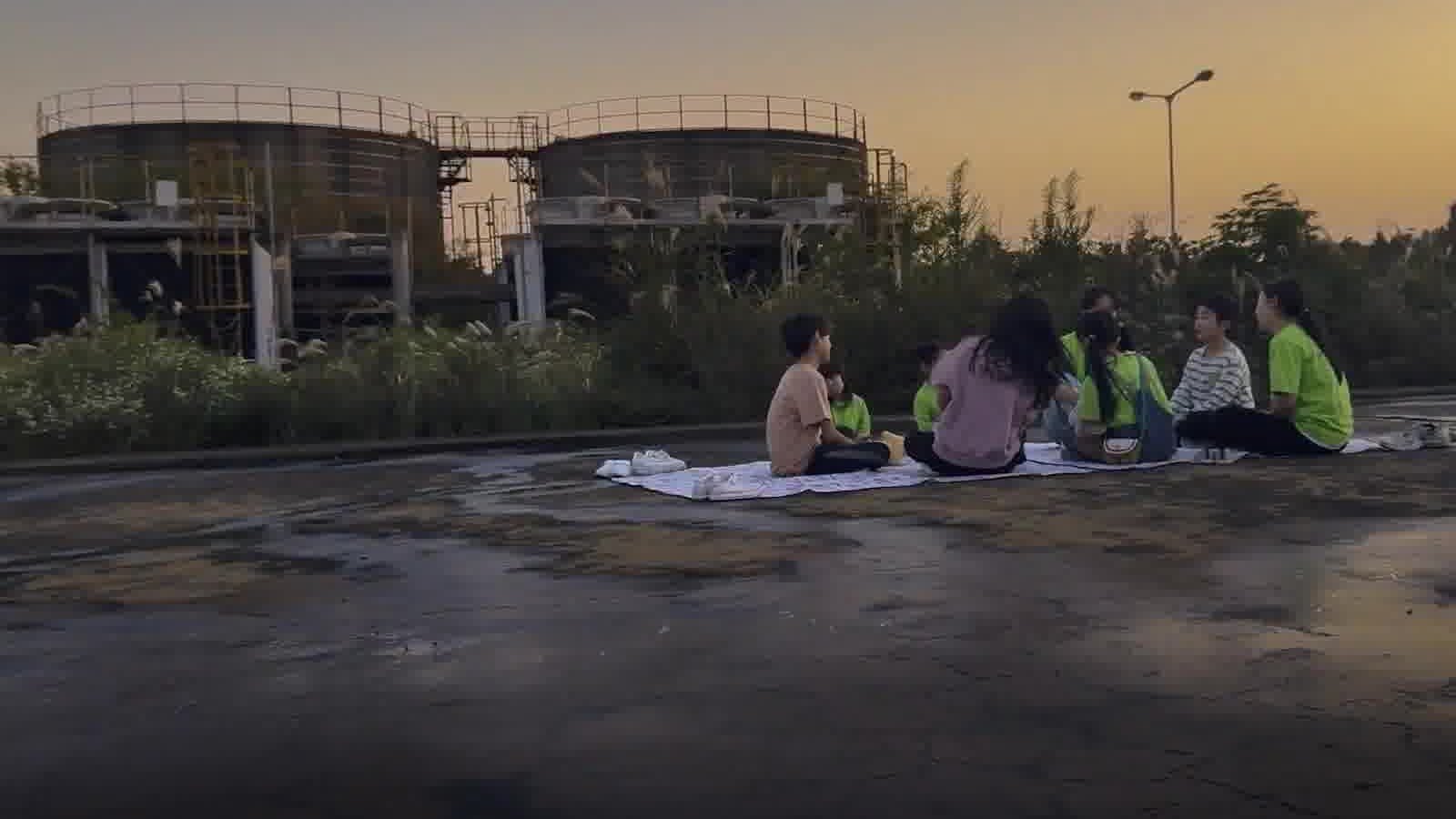 Sekelompok orang duduk di atas tikar saat senja dalam trailer final Possible Love