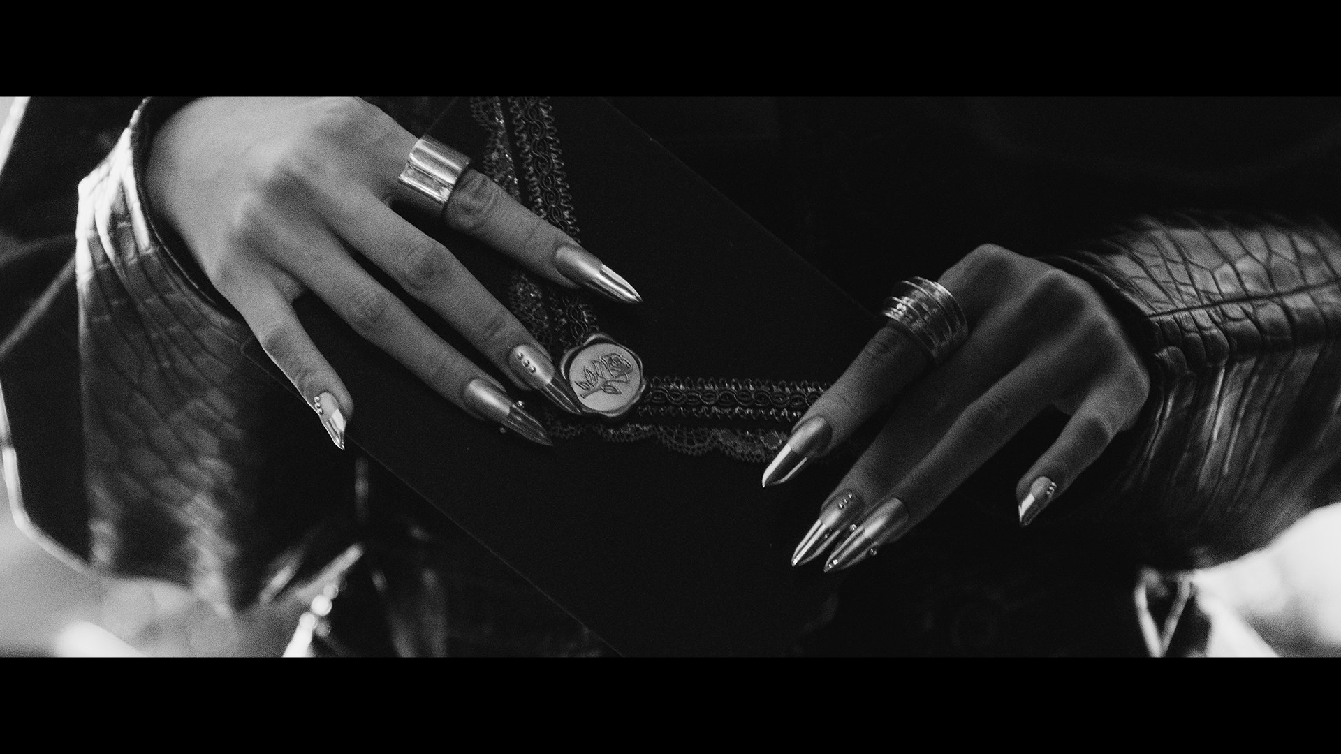 Tangan berkuku panjang perak dengan cincin dalam visual hitam putih PRESS PLAY